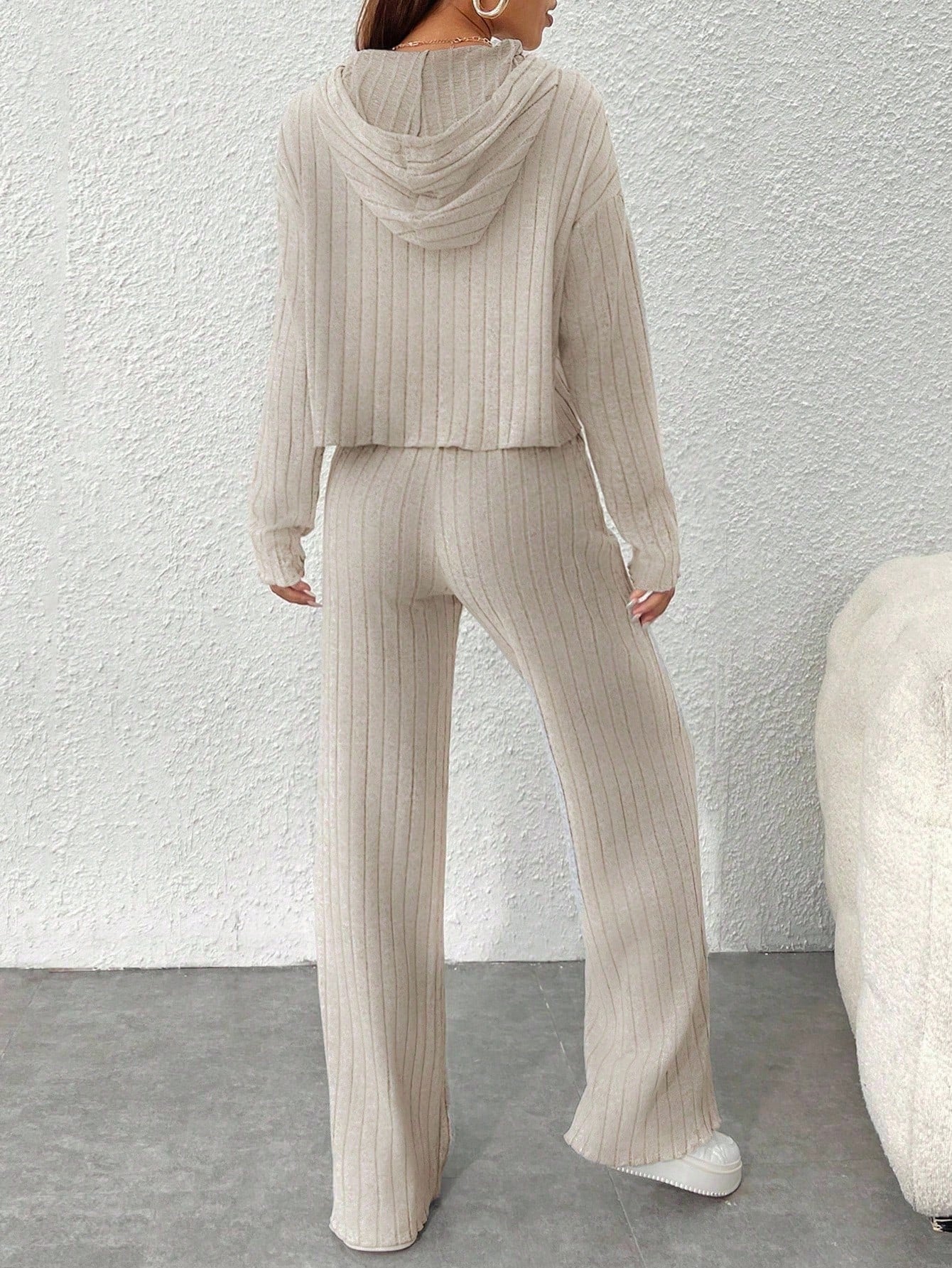 Person wearing a beige ribbed knit outfit against a white wall. Nushes