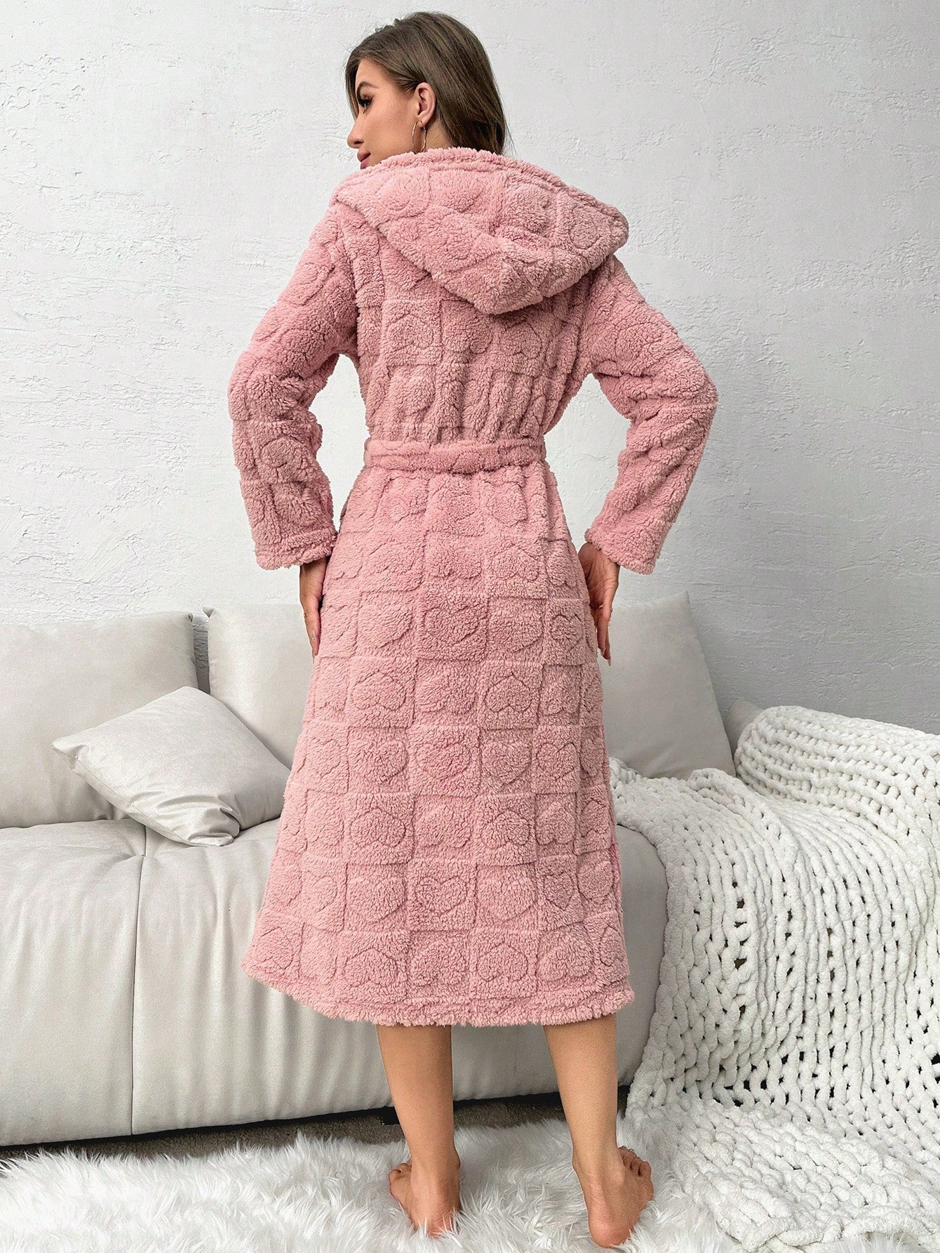 Woman wearing a pink textured robe in a cozy living room setting.