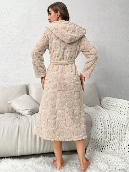 Woman wearing a beige textured robe in a cozy living room setting.