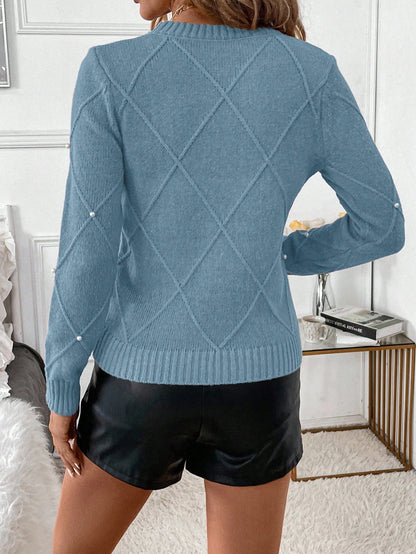 Person wearing a blue sweater with a diamond pattern and black shorts in an indoor setting.Nushes