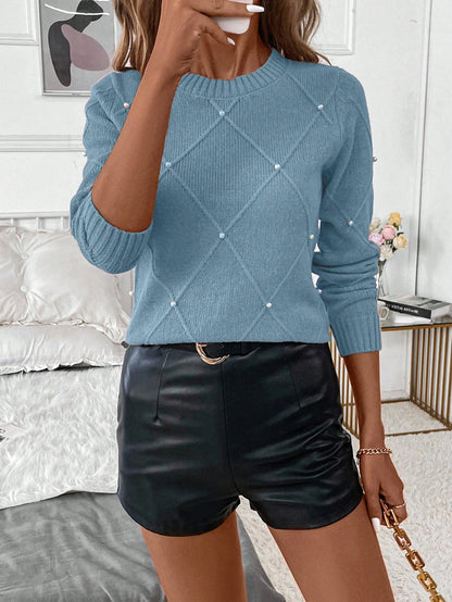 Person wearing a blue sweater with diamond pattern and black leather shorts in a bedroom setting.Nushes