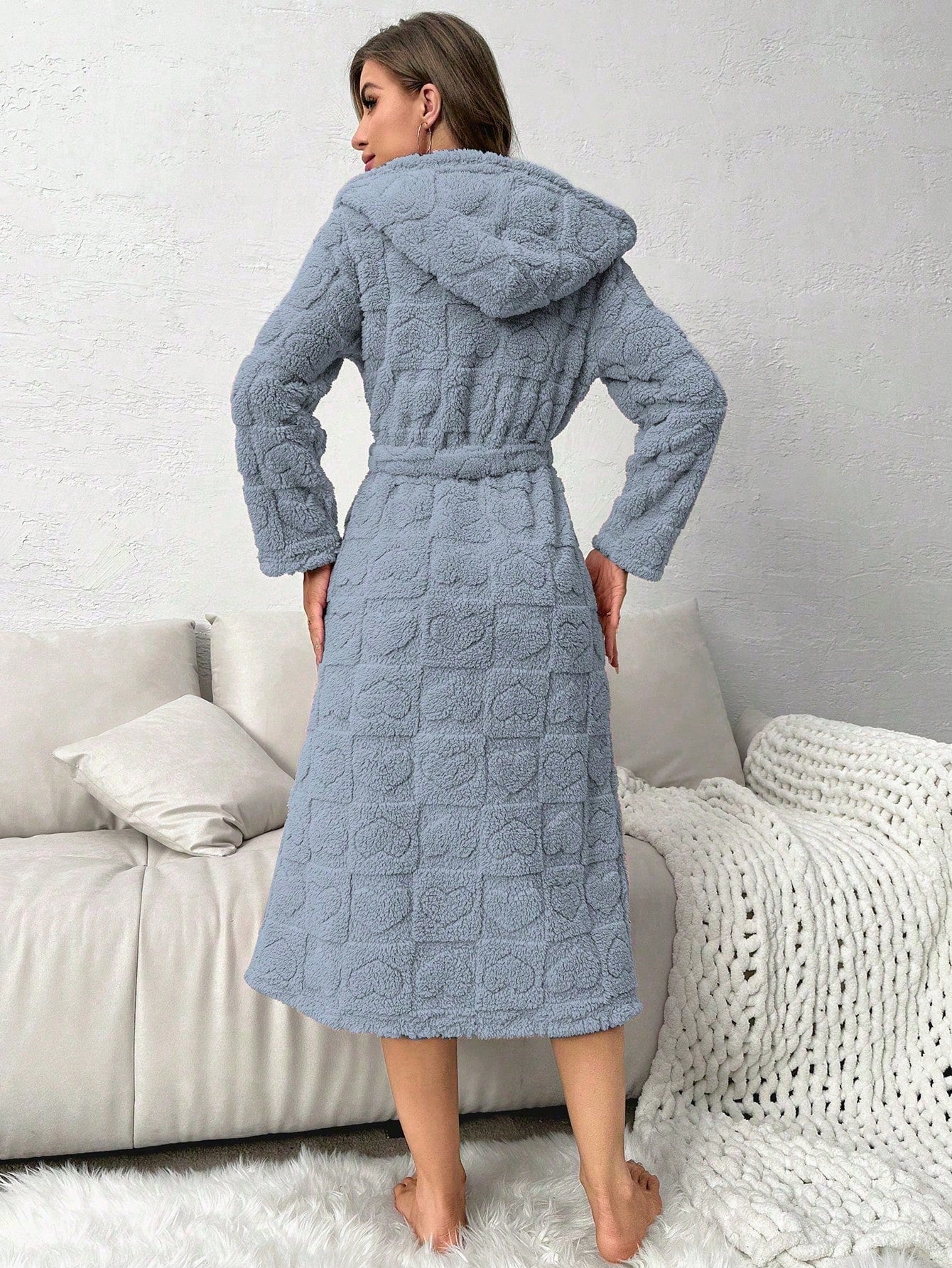 Woman wearing a textured blue robe standing in a living room.