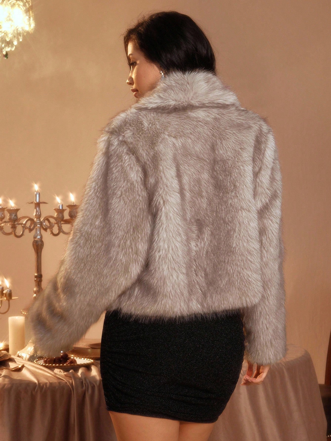 Woman wearing a gray fur jacket in an elegant indoor setting.