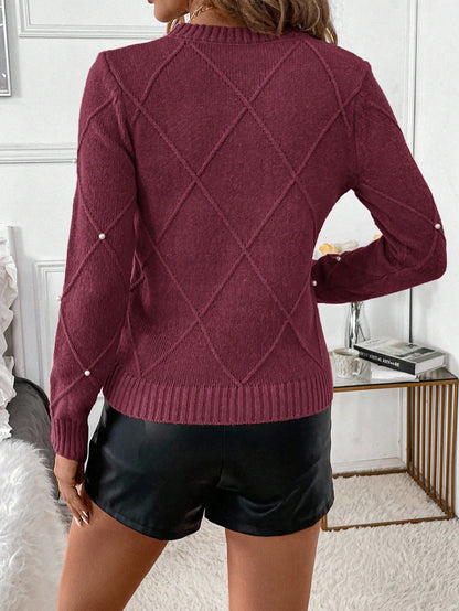 Person wearing a burgundy sweater with a diamond pattern and black shorts in an indoor setting.Nushes