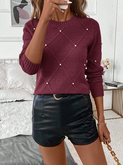 Person wearing a burgundy sweater with pearl embellishments and black leather shorts in an indoor setting.Nushes