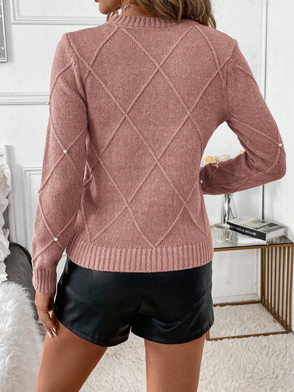 Person wearing a pink sweater with a diamond pattern and black leather shorts in a bedroom setting Nushes