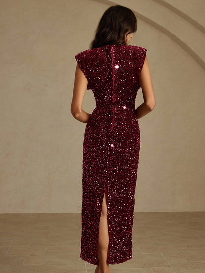 Woman wearing a burgundy sequin dress against a beige wall.